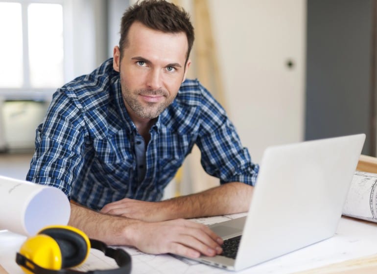 Construction worker sitting at his desk in front of his laptop